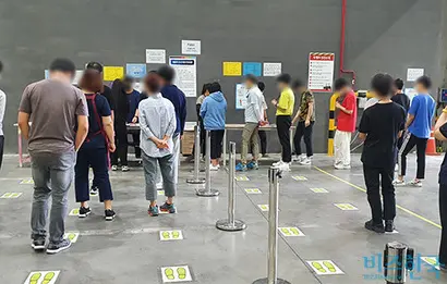 주간 조 업무 시작 전 출근을 등록하는 모습. 바닥에 1m 거리 유지를 위한 스티커가 붙어 있지만 제대로 지켜지지 않았다. 사진=김보현 기자