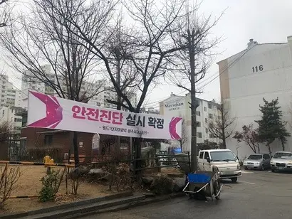 재건축 이슈가 있는 월드아파트를 매매하기 위해 수백 명의 사람들이 부동산을 찾았다. 사진은 월드아파트 단지에 걸려있는  재건축 안전진단 관련 현수막. 사진=박해나 기자