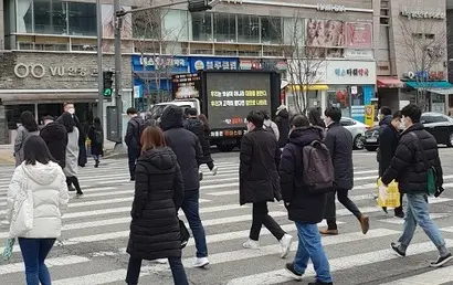 클로저스 시위 트럭 앞의 횡단보도를 건너는 시민들. 큼지막한 문구가 눈에 띄어 시민들의 이목을 끌기 쉽다. 사진=예스미디어 제공