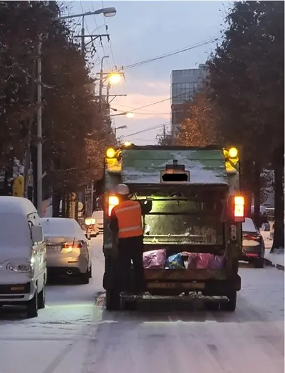 환경미화원이 불법 후미 발판에 매달려 이동하고 있다. 사진=한국노총 전국연합노동조합연맹