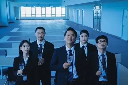 한 거라곤 무의미한 일밖에 없는데 최우수 부서로 선정되고 축배를 드는 ‘메타버스유비쿼터스NFT디지털컨버젼스빅러닝TF부’ 사람들. 그런데 생각해 보면 일반 회사에서도 ‘대체 이거 뭐하는 짓거리이지?’ 싶은 무의미한 일들이 꽤나 많다. 보여주기 위한 회의, 보여주기 위한 보고서 같은. 사진=왓챠 제공